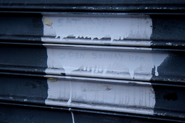 A misspelt message written on the shutter saying 'open Sonday'